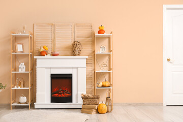 Wall Mural - Interior of stylish room with shelving units and autumn decorations on modern fireplace near beige wall