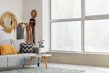 Wall Mural - Interior of living room with clothes rack, sofa and window