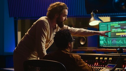 Fototapete - Tracking engineer collaborating with musician to edit sounds in studio control room, recording tunes to create a new album. Audio expert operating audio mixer and controller. Camera A.