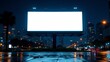 © mischenko - Blank billboard stands alone on a city street at night with moving traffic and illuminated buildings in the background