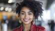 © Ari - Afro business woman in red leather jacket smiling at the airport baggage claim area
