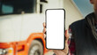 © VAKSMANV - Truck driver holding smartphone mockup of blank screen.
