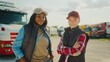 © VAKSMANV - Two women standing besides each other while looking at camera and smiling. Waiting for new delivery location instructions. People having break while working in logistics and transportation.