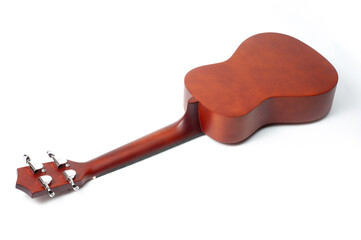 Ukulele made of natural wood of dark color photographed on a white background.