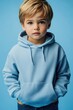 © Alexander Chaykin - Youthful boy with blonde hair, blue hoodie and hands in pockets posing against a light-blue background.
