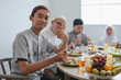 © Gatot - Portrait Of Young Teenage Boy Eating Food And Giving Thumb Up Showing Tasty Reaction During Lunch With Family On Eid Mubarak Moment