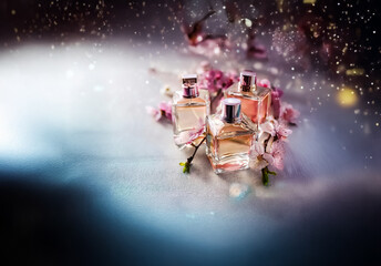 Poster - Elegant perfume bottles showcased with soft pink blossoms and shimmering glitter against a dark backdrop. A luxurious and glamorous display.