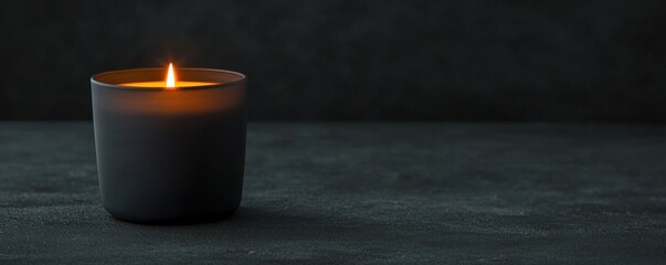 Poster - Elegant black candle glowing softly on a dark background, creating a serene and calming atmosphere for relaxation