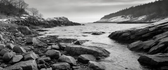 Aufkleber - Monochrome landscape with rocky shore and calm water under cloudy sky in winter season with trees in background and high contrast black and white photography
