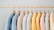 © Alena - A row of knit sweaters on wooden hangers, sorted by color from blue to cream. Soft and cozy fabrics.