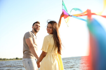 Wall Mural - Happy couple playing with kite near sea. Spending time in nature