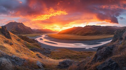 Wall Mural - Dramatic sunset over a meandering river in a mountainous landscape.