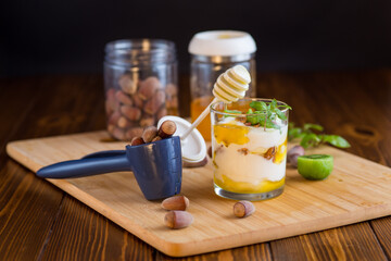 Wall Mural - homemade yogurt with kiwi, honey and nuts in a glass on a wooden table