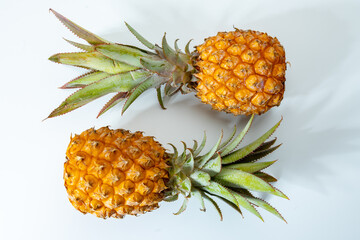 Wall Mural - Two whole fresh ripe pineapples or sweet baby ananas on white background close up