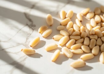 Wall Mural - pine nuts scattered loosely on a white marble countertop, with soft light shadows falling across