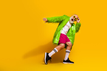 Canvas Print - Eccentric Senior Man Posing in Vibrant Green Fur Coat against Yellow Background