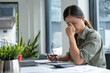 © MIND AND I - Businesswoman sitting at desk on couch in workplace or at home working on laptop and analyzing data on charts and graphs and writing on papers to make business plan and strategies for company