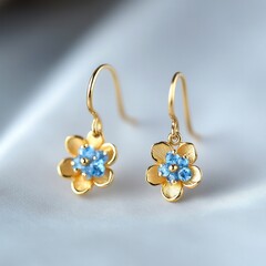 Wall Mural - Elegant gold flower earrings with blue gemstones on soft fabric surface