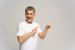 © muse studio - Cheerful older man smiles and points excitedly in a light studio setting during a casual moment