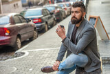 Man drinking morning coffee. Coffee break. Everyday style routine. Bearded man having coffee in city street. Handsome man on street holding cup of coffee. Business lifestyle, break. Relax outdoor