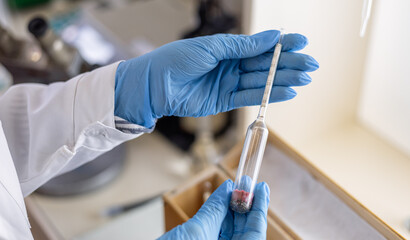 a female chemist takes a hydrometer to subsequently measure the density of a liquid by immersing the