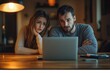© stockphoto02 - A young couple looks concerned at their laptop screen, perhaps facing an unexpected problem or bad news.