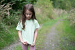 © PeterPike - Little sad girl in a t-shirt on a forest road in summer. Concept of a lonely child and sadness