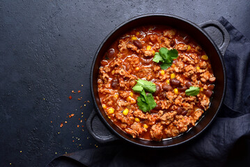 Wall Mural - Chili con carne - traditional mexican minced meat and vegetables stew in tomato sauce in a cast iron pan. Top view with copy space.