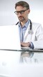 © rogerphoto - Doctor man in a blue shirt under a medical coat is using technology in medicine. Portrait of physician typing on a laptop on a glass desk in clinic, vertical view. Medicine and science