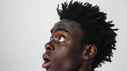 Wall Mural - Young man with expressive face looking upwards in a minimalist studio setting, conveying surprise or curiosity