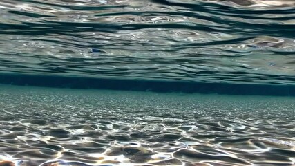 Poster - Underwater view of rippling clear water surface with sandy ocean floor, serene nature and tranquility concept