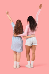 Wall Mural - Beautiful young female friends on pink background, back view