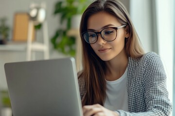 Wall Mural - A woman in glasses using a laptop computer