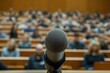 © Alena - A lecture hall filled with students and faculty members, with a microphone at the front
