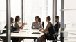 © fizkes - Diverse group of business colleagues gathered around conference table, engaged in discussion, focused on planning, implementing strategic actions to growth company revenue. Negotiations, collaboration
