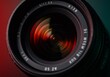 © Alper AI - Extreme close-up of a camera lens with vibrant colors and a reflective metal ring, showing intricate details and a blurred, colorful background.