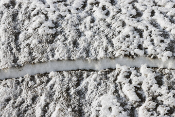 Wall Mural - textured abstract background of curved white line on rough, grainy snow on sand