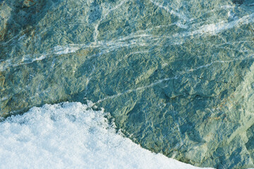 Wall Mural - fresh white winter snow on natural green rock abstract textured background