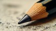 © senadesign - Close-up view of a sharpened pencil resting on textured paper with faint sketches