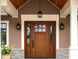 © Rhony - A front door detail of a brown modern farmhouse with a brown front door, black light fixtures, and a covered porch.