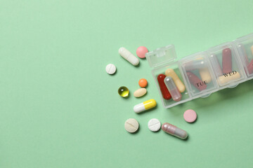 Wall Mural - Plastic container with various pills on green background