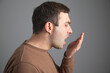 © andranik123 - Man checks his breath with his hand. The concept of halitosis