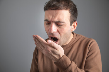 Man checks his breath with his hand. The concept of halitosis