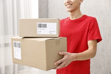 Poster - Man holding parcels with shipping labels indoors, closeup