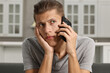 © New Africa - Stressed man calling hotline for mental health help on sofa in kitchen