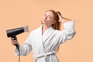 Wall Mural - Beautiful young woman drying her hair with hairdryer on beige background