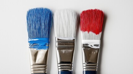 Wall Mural - three paintbrushes with different colors - blue, white, and red. The background is a plain white surface. The image appears to be taken from a top-down perspective