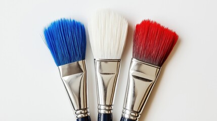 Wall Mural - three paintbrushes with different colors - blue, white, and red. The background is a plain white surface. The image appears to be taken from a top-down perspective