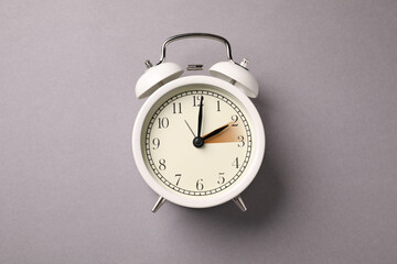 Poster - Daylight saving time. White alarm clock on grey background, top view. Highlighted area showing time change by one hour forward