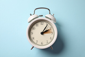Poster - Daylight saving time. White alarm clock on light blue background, top view. Highlighted area showing time change by one hour forward